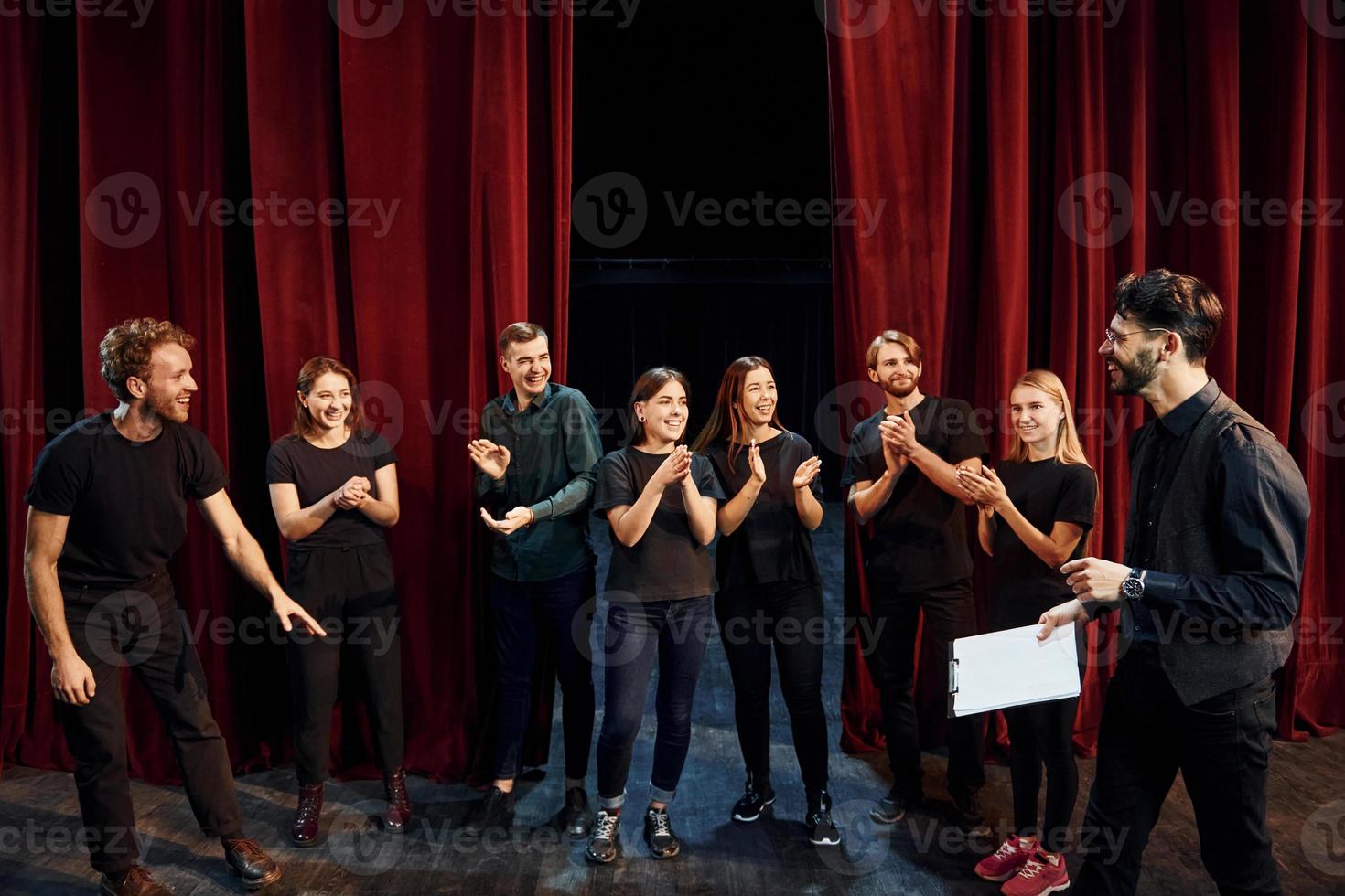 Mann übt seine Rolle. Gruppe von Schauspielern in dunkler Kleidung bei der Probe im Theater foto