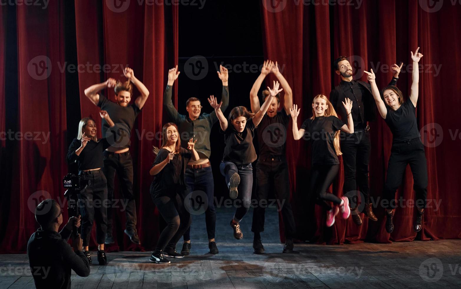 glückliche menschen, die erfolg feiern. Gruppe von Schauspielern in dunkler Kleidung bei der Probe im Theater foto