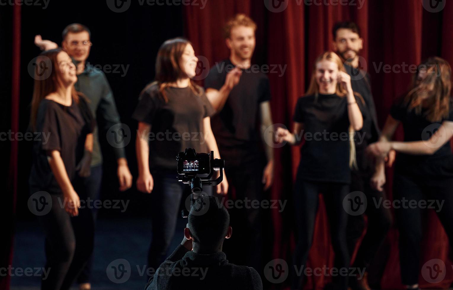 glückliche menschen, die erfolg feiern. Gruppe von Schauspielern in dunkler Kleidung bei der Probe im Theater foto