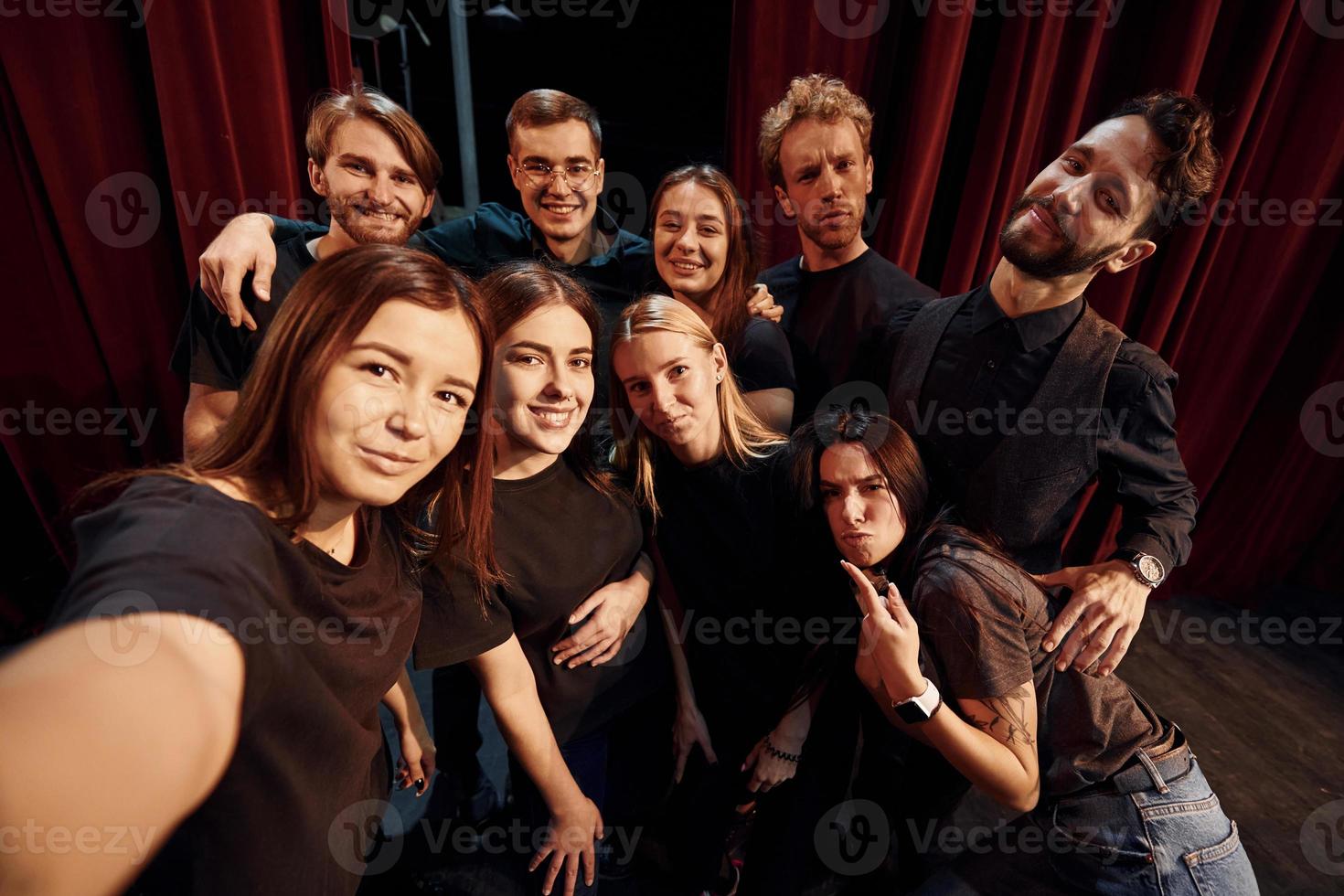 Selfies machen. Gruppe von Schauspielern in dunkler Kleidung bei der Probe im Theater foto