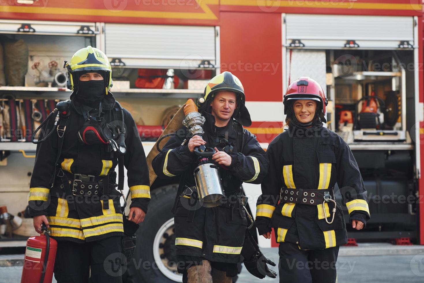 Gruppe von Feuerwehrleuten in Schutzuniform, die sich im Freien in der Nähe eines Lastwagens befinden foto