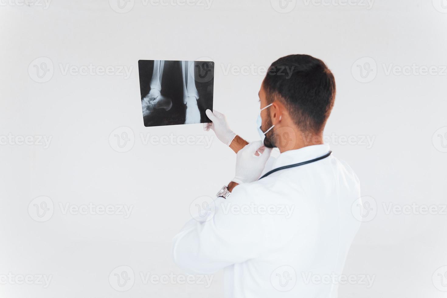 Sanitäter mit Röntgen. junger gutaussehender Mann, der drinnen vor weißem Hintergrund steht foto