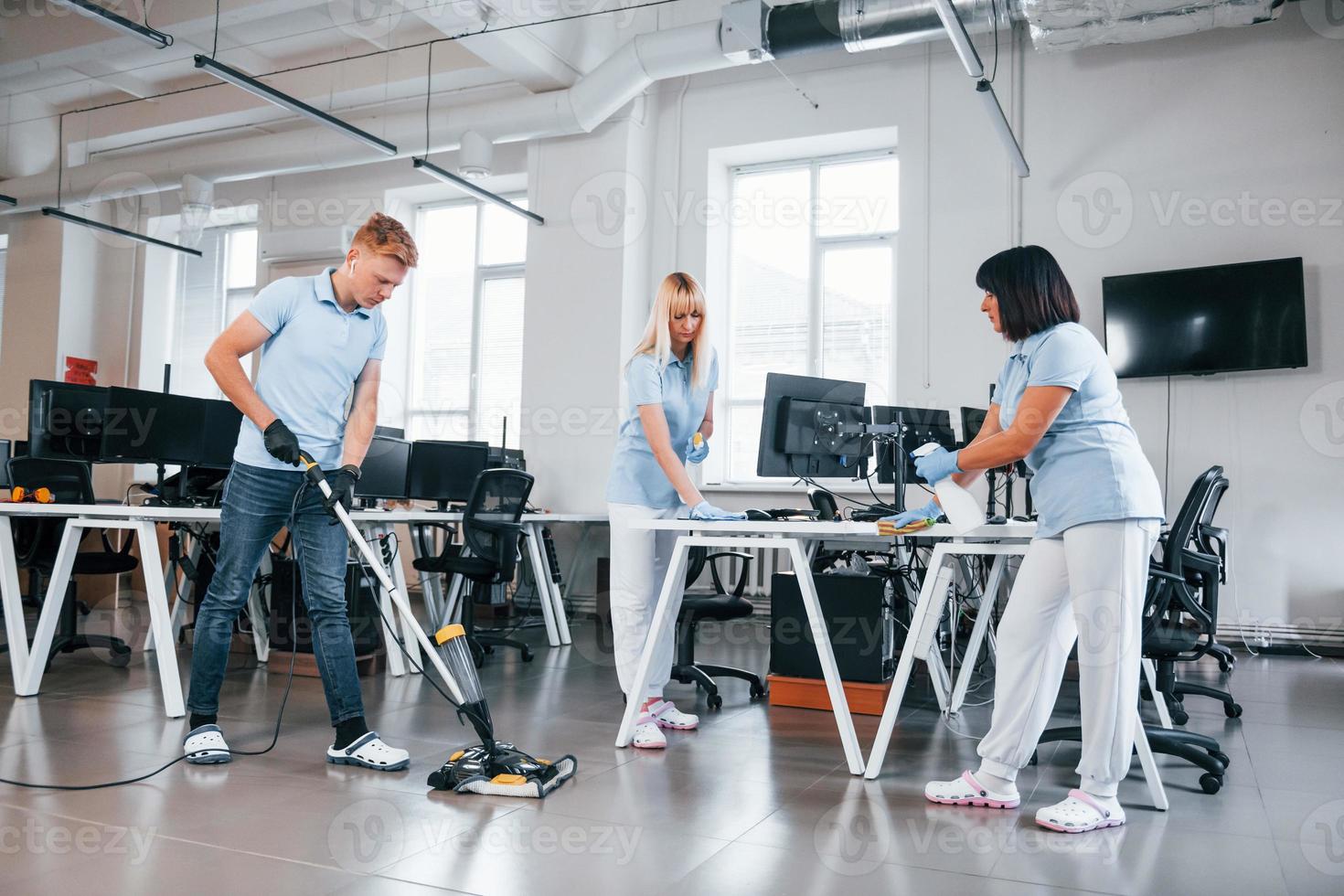 reinigt den Boden. gruppe von arbeitern reinigt tagsüber gemeinsam ein modernes büro foto