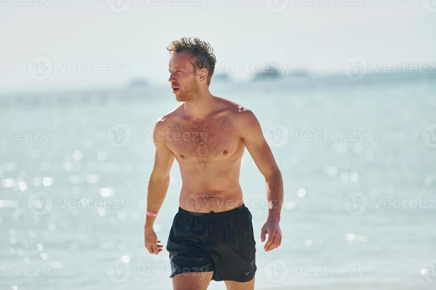 klares Wasser. junger europäischer mann hat urlaub und genießt die freizeit am strand des meeres foto