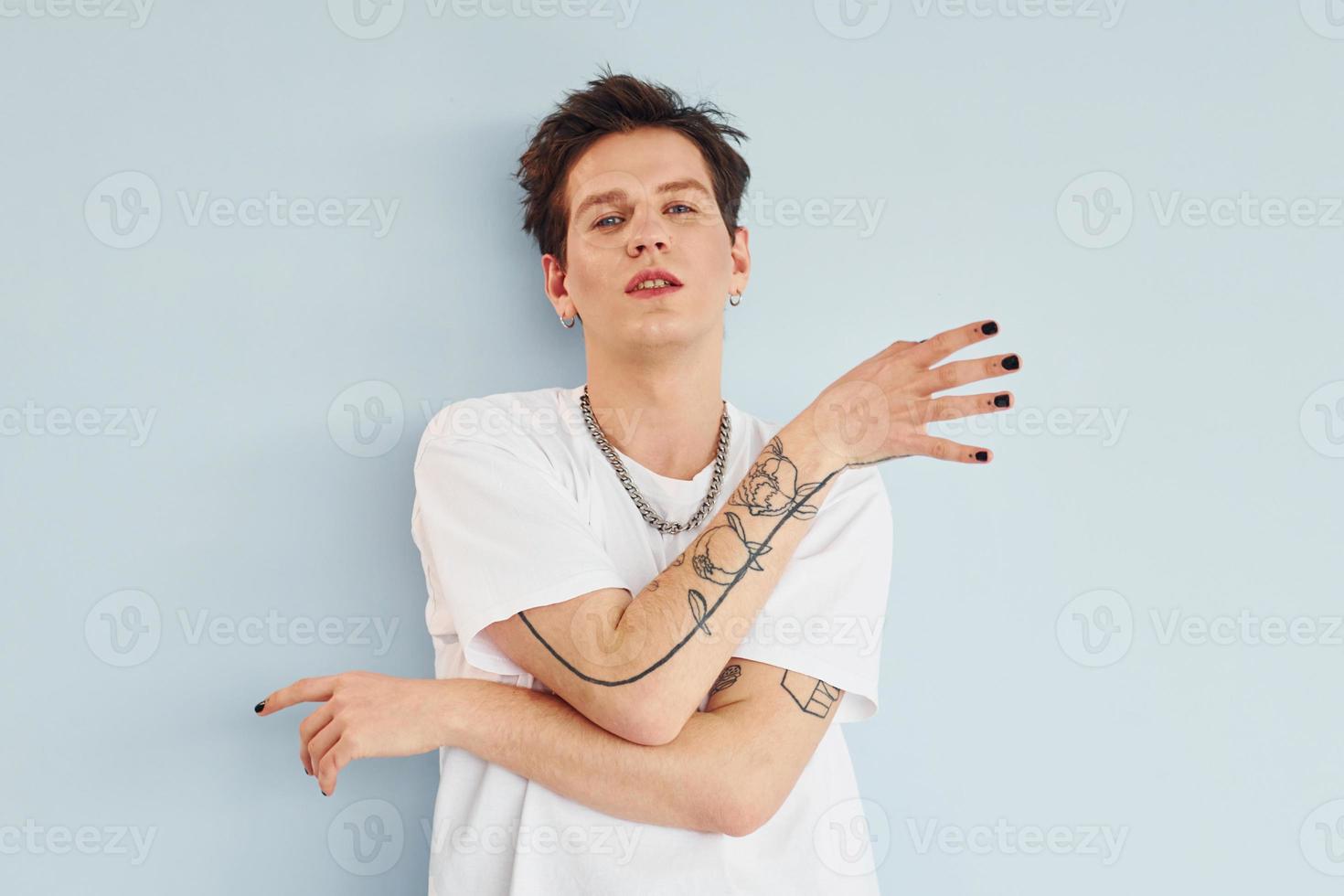 junger schwuler mann steht im studio und posiert für eine kamera. rot gefärbte Lippen foto