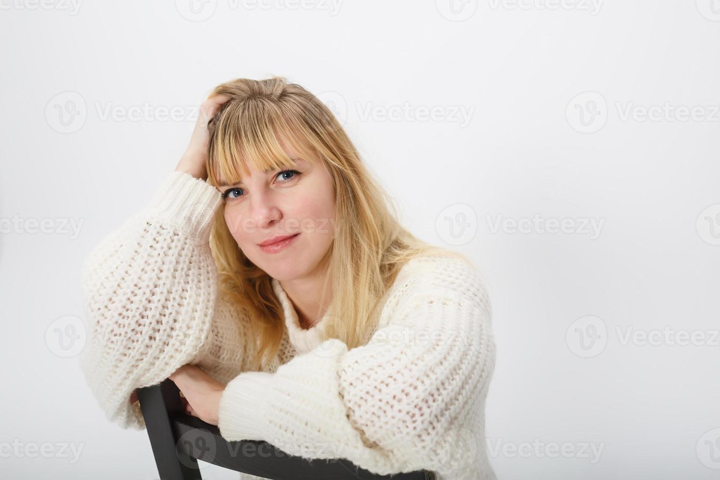 Schließen Sie herauf Porträt des blonden Mädchenmodells im weißen Wollpullover auf weißem Hintergrund im Studio foto