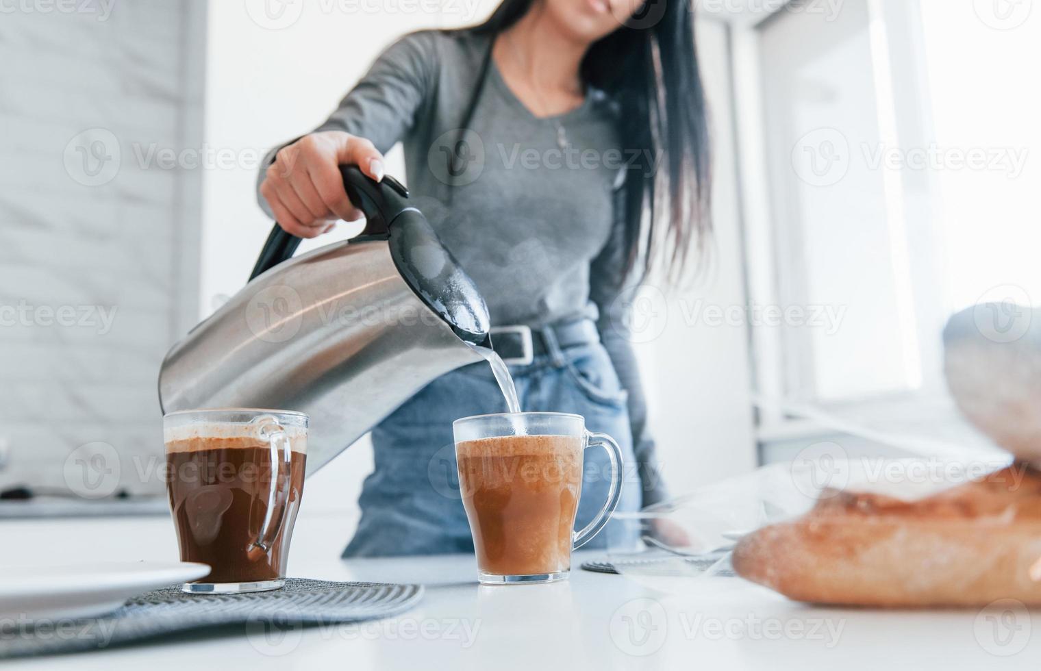 Wasser gießen. junge frau ist tagsüber drinnen im raum eines modernen hauses foto