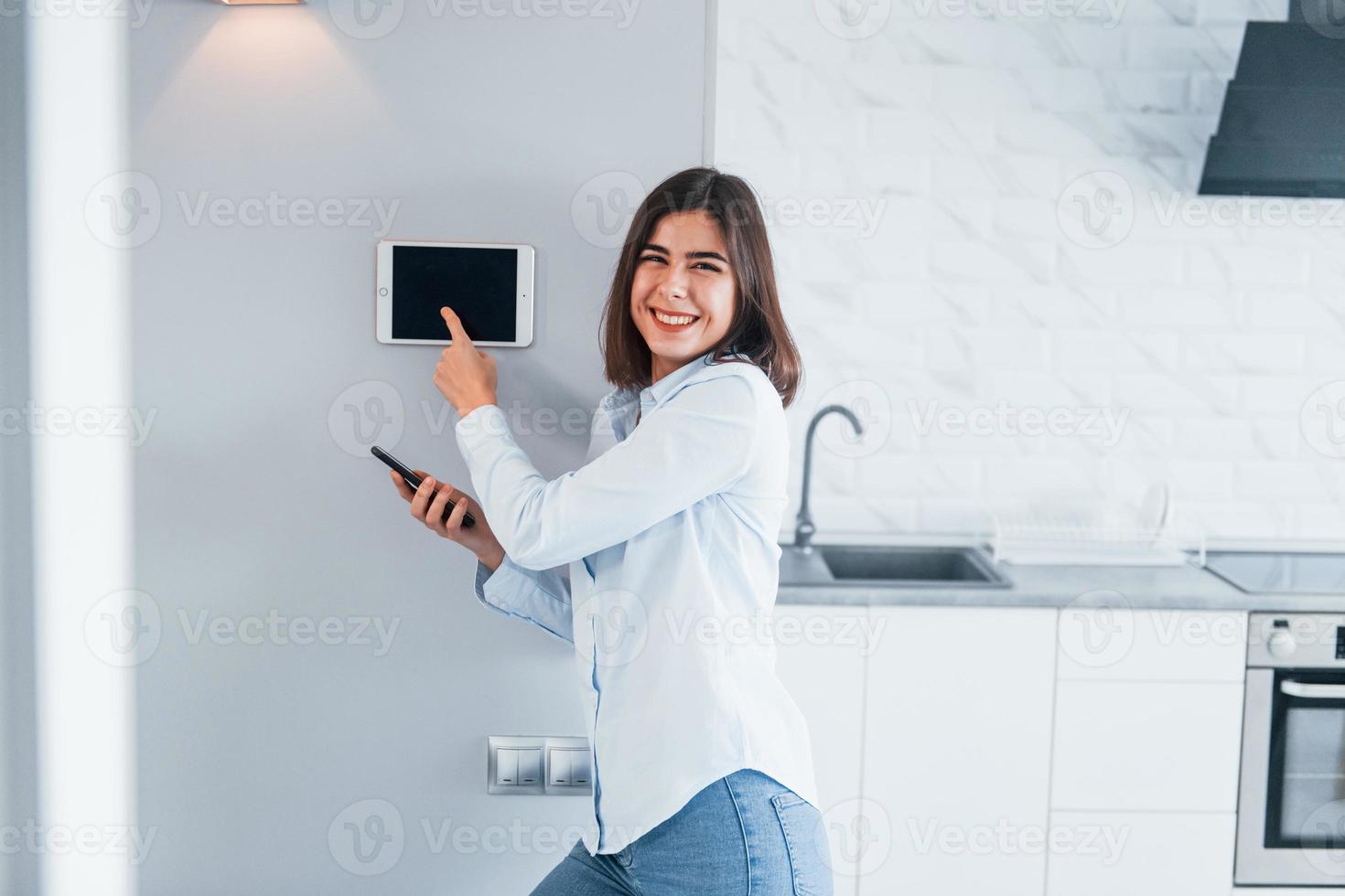 Steuern des Hauses durch eine Berührung. junge frau ist tagsüber drinnen im smart house room foto