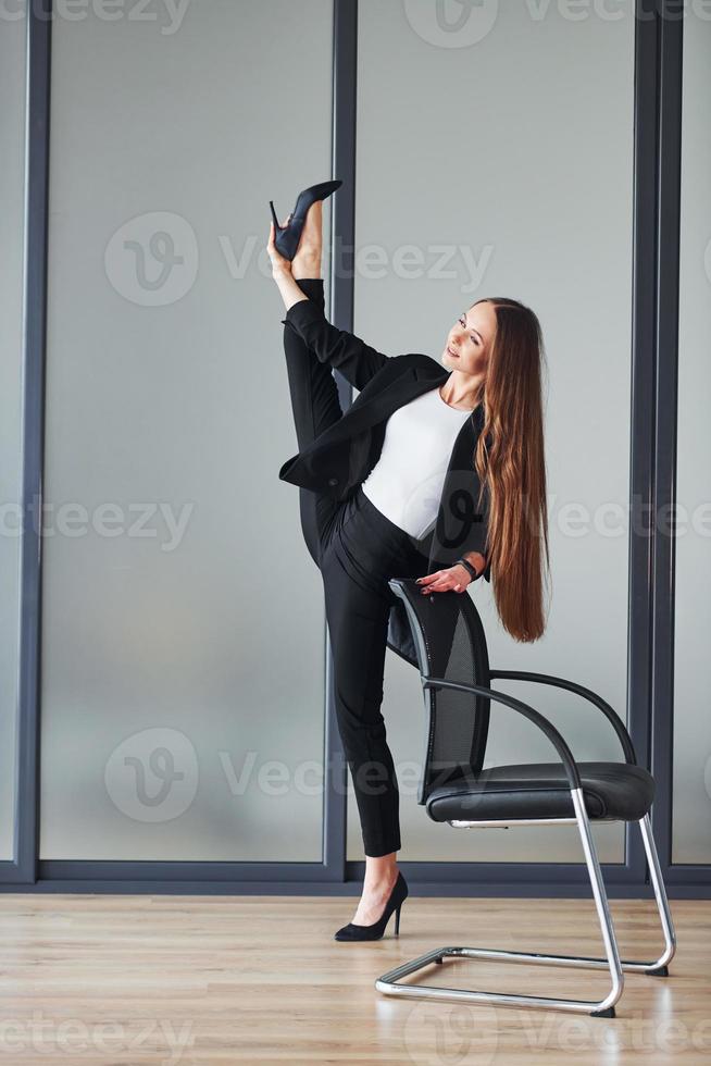 Junge erwachsene Frau in formeller Kleidung ist drinnen vor grauem Hintergrund foto