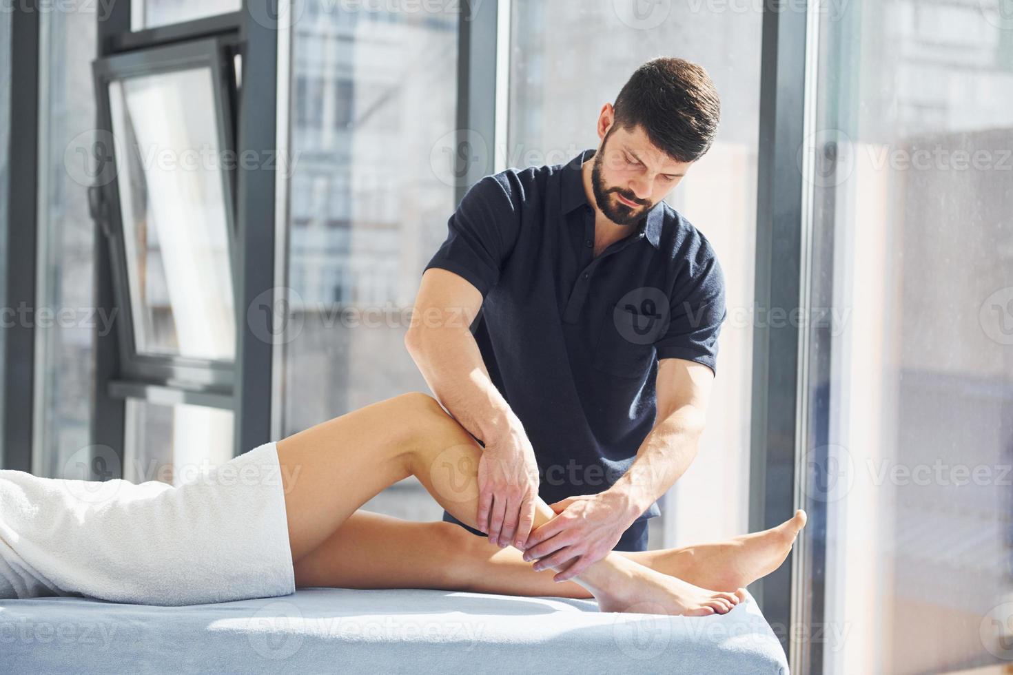 Typ macht Beinmassage. junge frau liegt, wenn mann sie im spa bedient foto