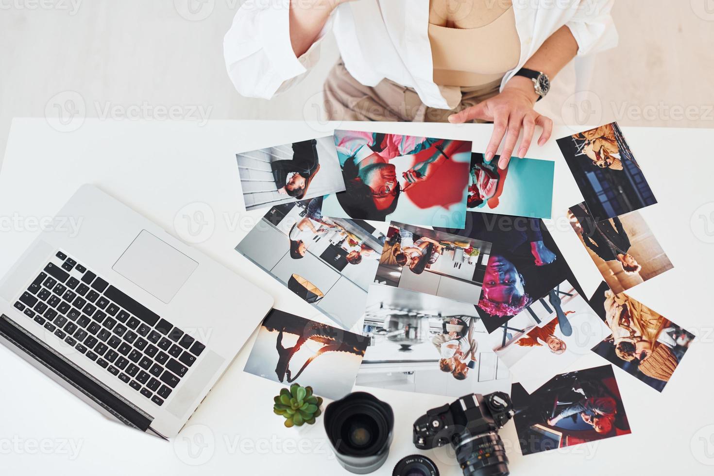 Nahaufnahme des Tisches mit Kamera und Fotos. Fotografin bei der Arbeit foto