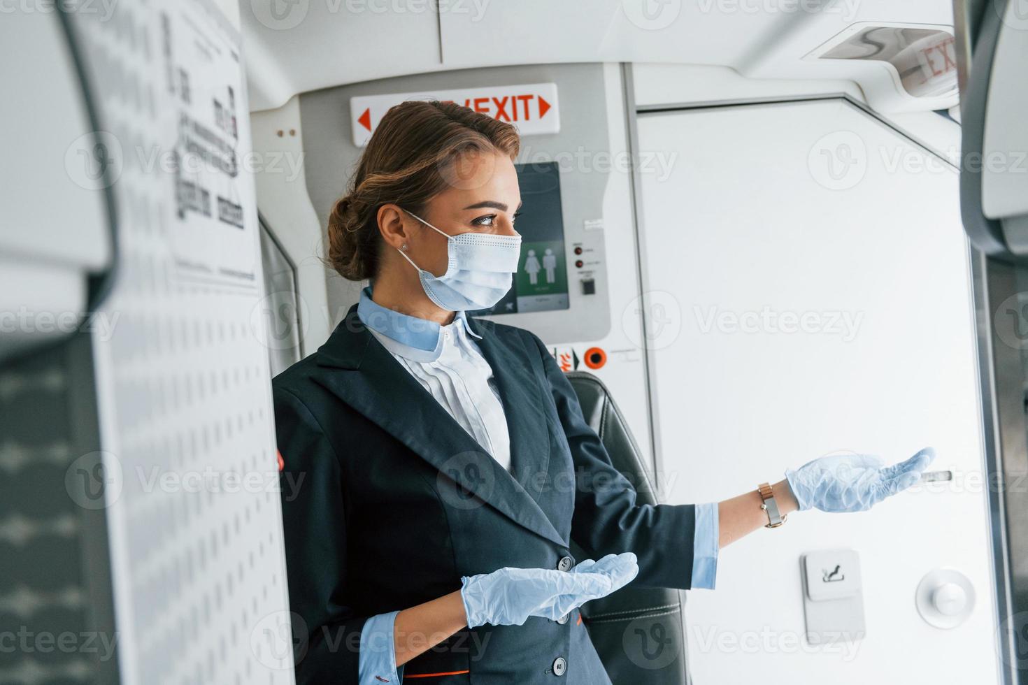 in Schutzhandschuhe und Maske. junge Stewardess über die Arbeit im Passagierflugzeug foto