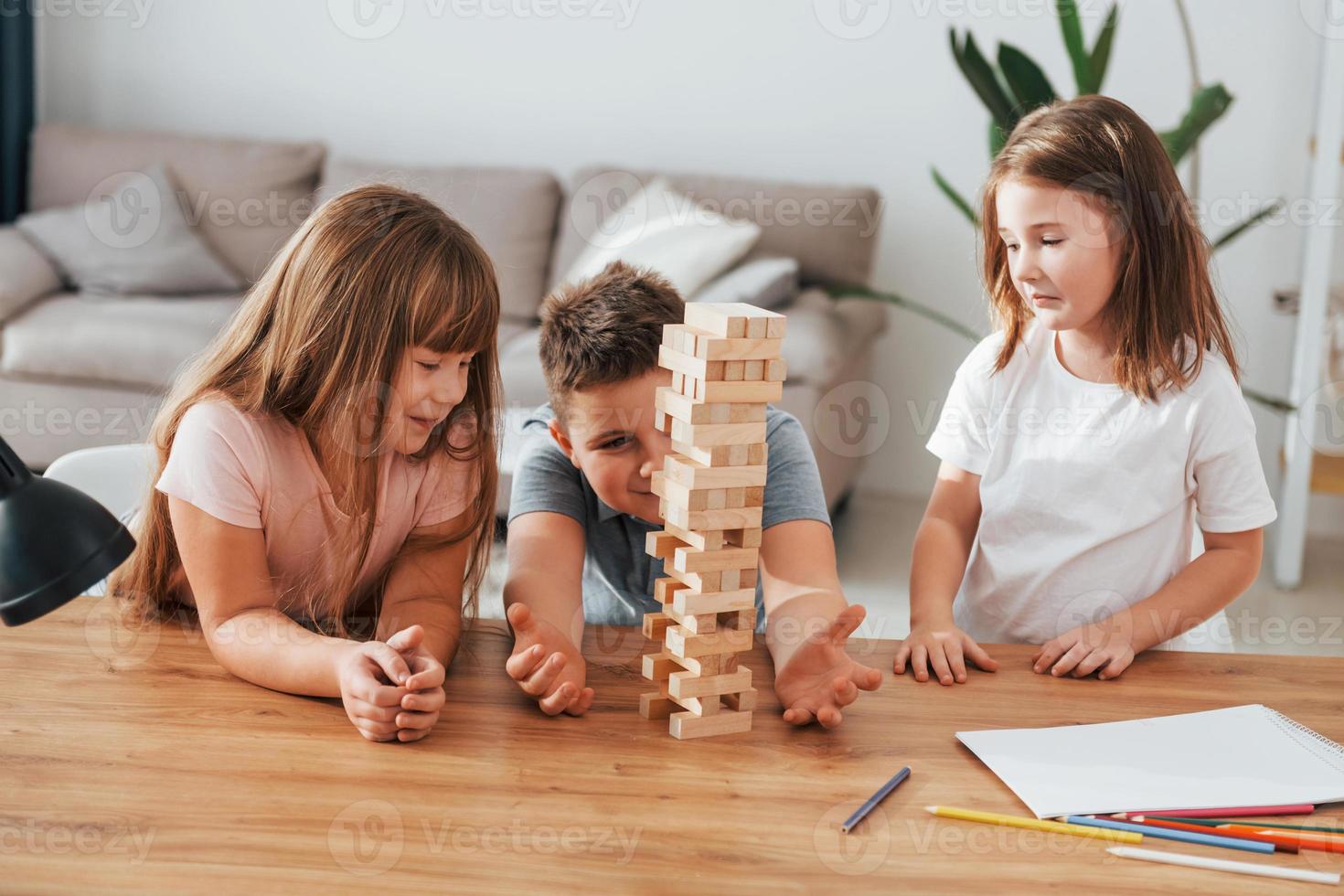 Spiel mit dem jumpelnden Turm. Kinder, die sich tagsüber gemeinsam im Wohnzimmer amüsieren foto