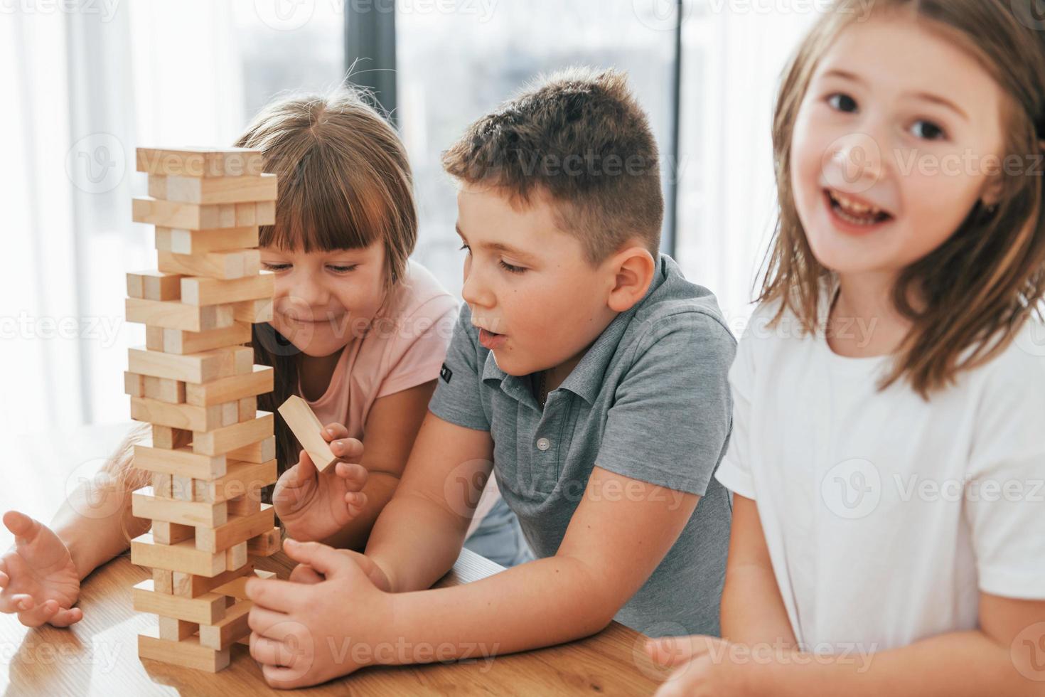 konzentrierte sich auf das Jumbling Tower-Spiel. Kinder, die sich tagsüber gemeinsam im Wohnzimmer amüsieren foto