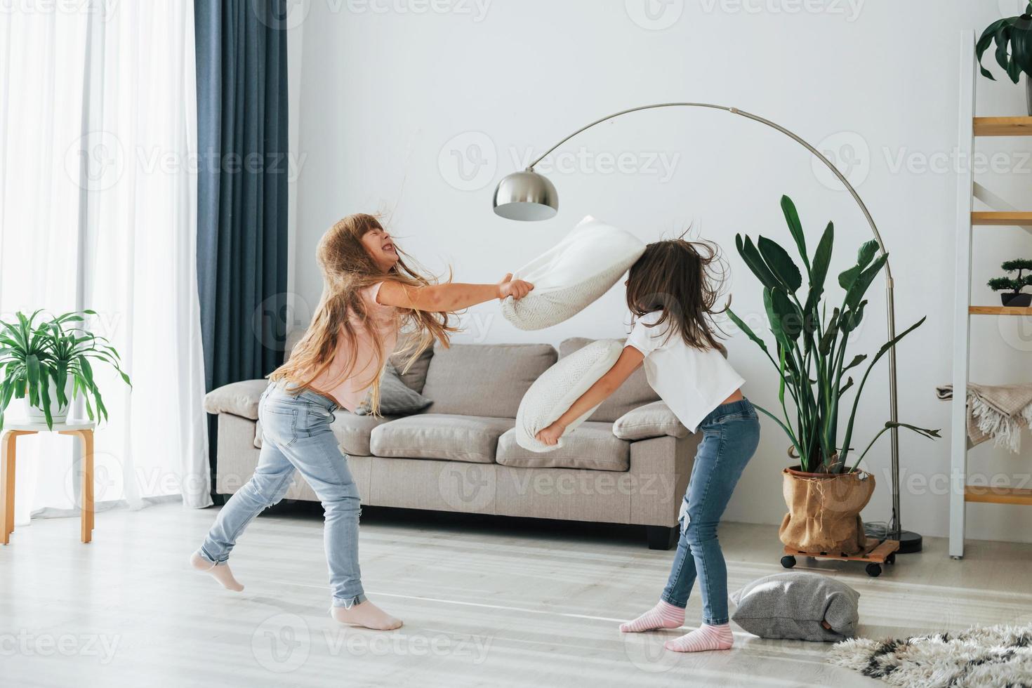 Mädchen spielen ein Kissenschlachtspiel. Kinder, die sich tagsüber gemeinsam im Wohnzimmer amüsieren foto