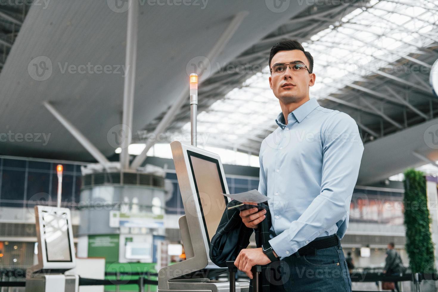 am Terminal stehen. Der junge Geschäftsmann in formeller Kleidung ist tagsüber am Flughafen foto