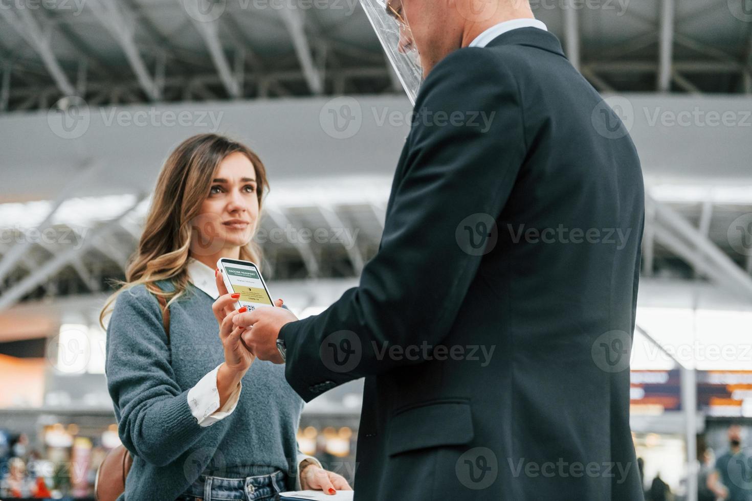 männlicher arbeiter, der frau hilft. junge weibliche touristin ist tagsüber am flughafen foto