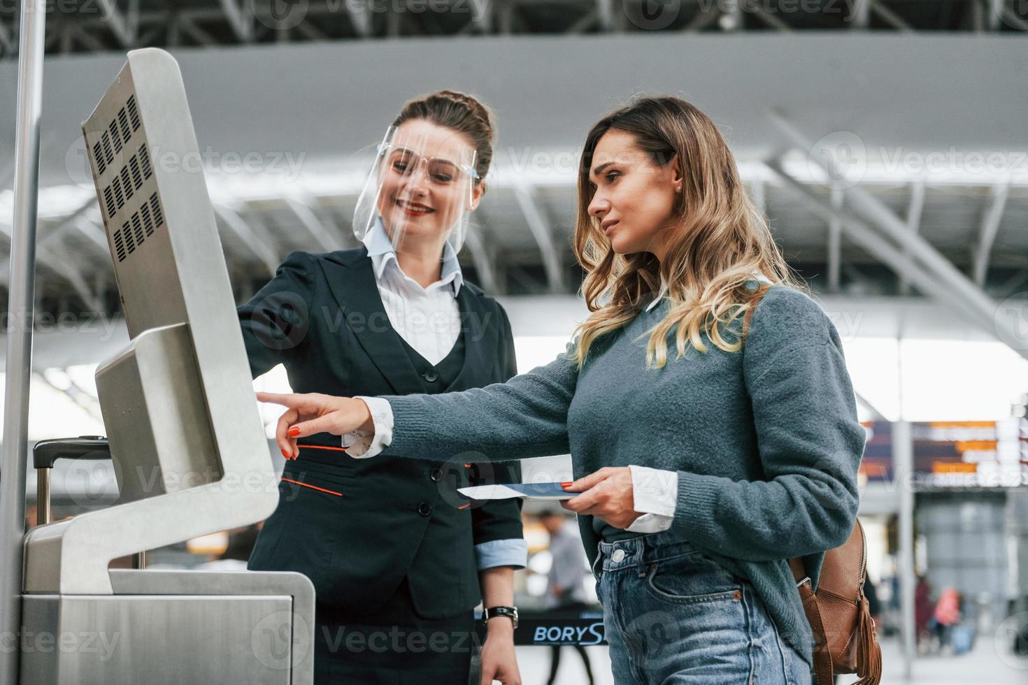 Mitarbeiter hilft bei der Nutzung des Terminals. junge weibliche touristin ist tagsüber am flughafen foto