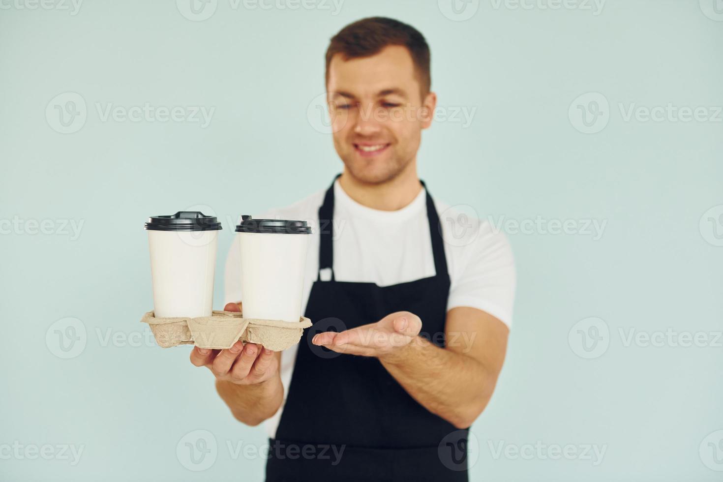 Mann in Uniform steht mit Getränken in der Hand im Studio foto