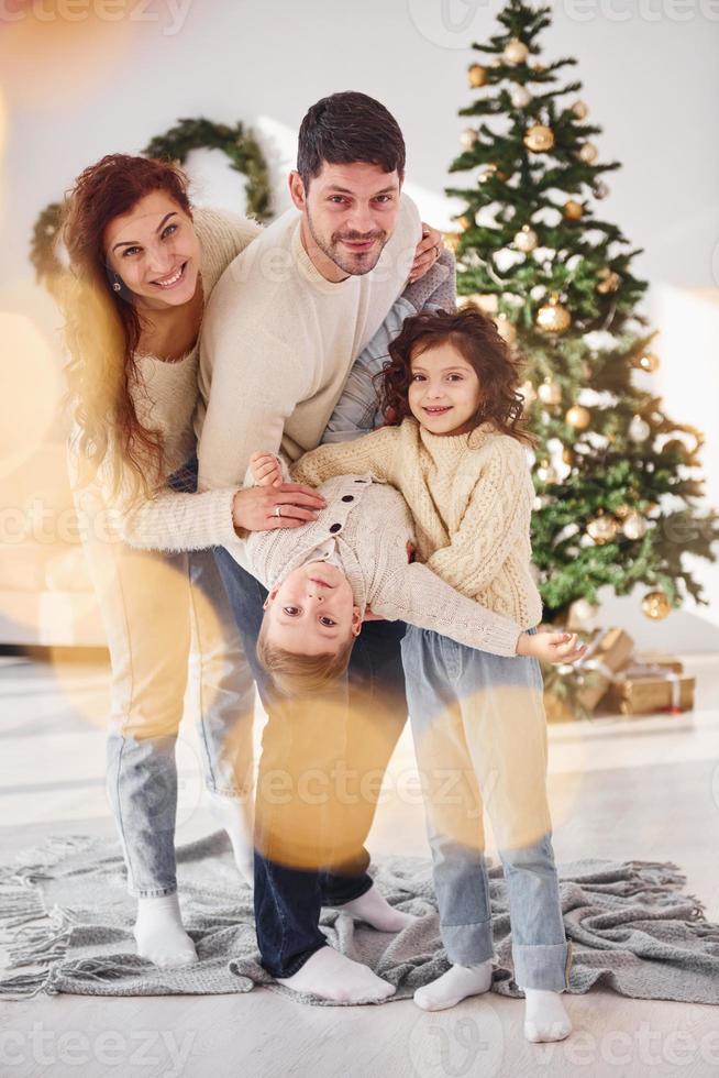 im Wohnraum stehen und Jungen in den Händen halten. familie feiert neujahr mit ihren kindern zu hause foto