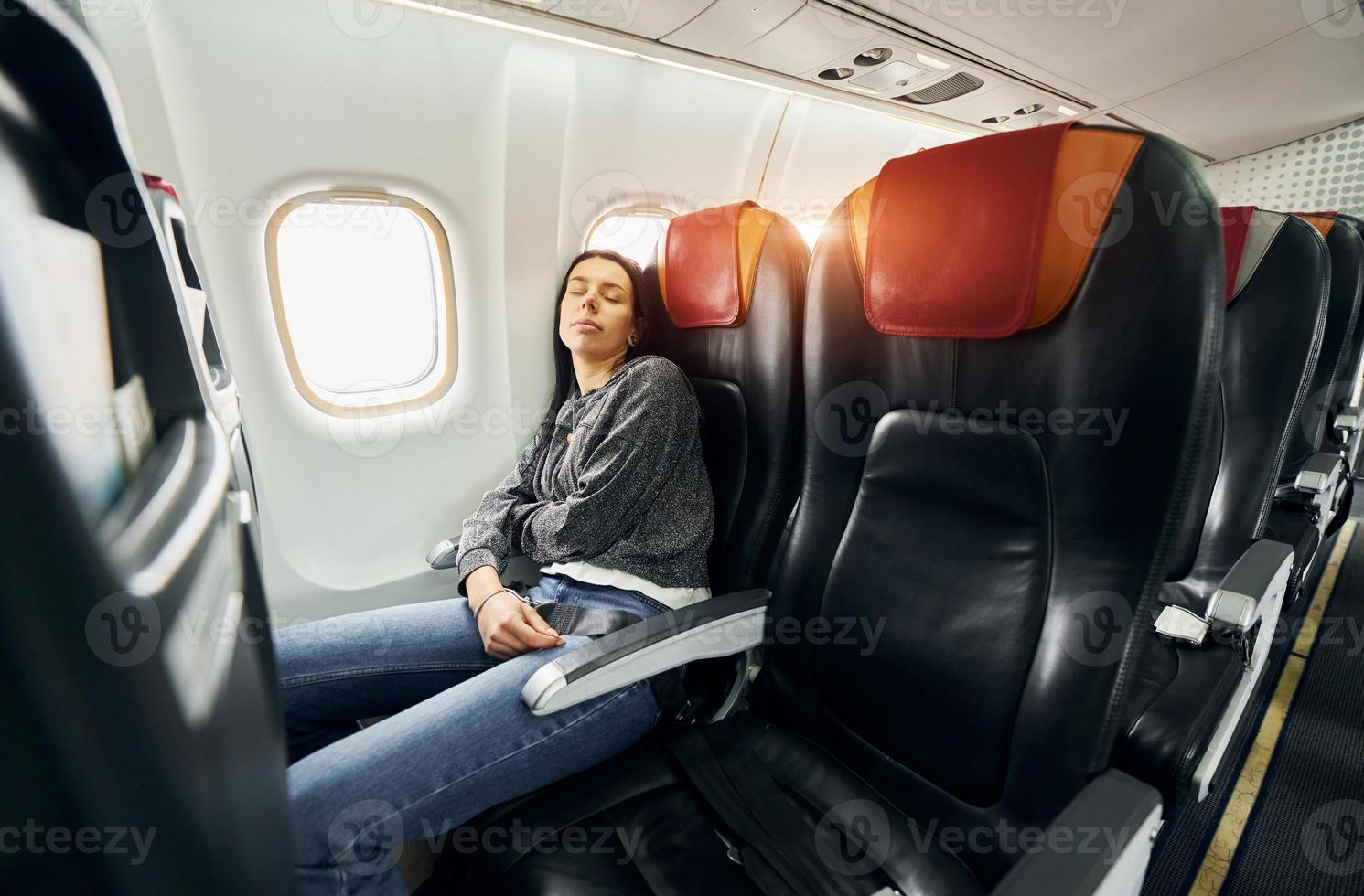 Junge Frau in Freizeitkleidung schläft auf dem Beifahrersitz im Flugzeug foto