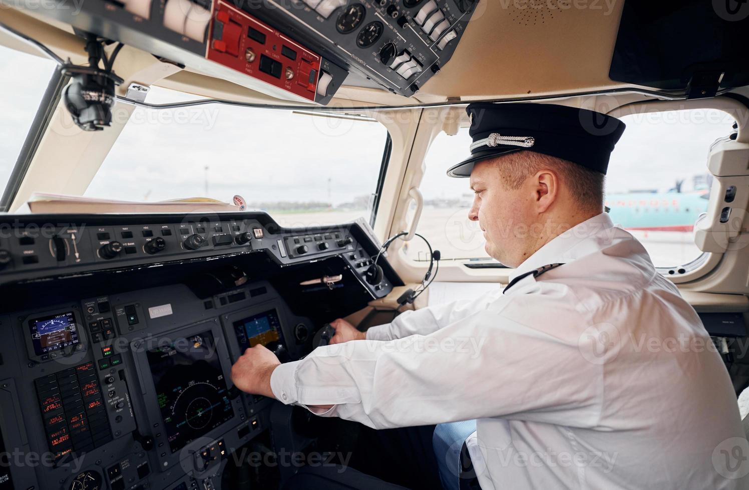 Pilot in formeller Kleidung sitzt im Cockpit und steuert Flugzeug foto