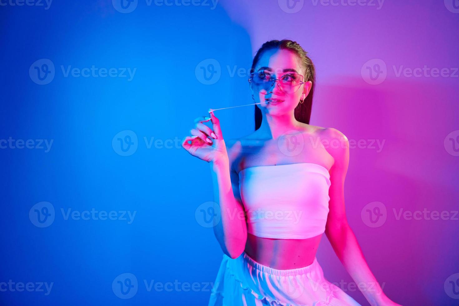 positive Gefühle. modische junge frau, die im studio mit neonlicht steht foto