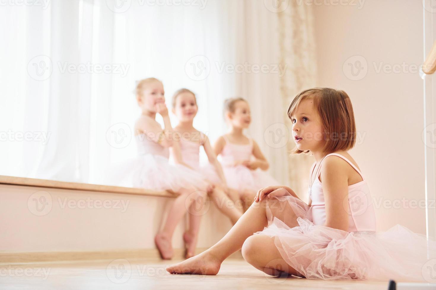 Mädchen sitzt auf der Fensterbank und auf dem Boden. kleine ballerinen, die sich auf die leistung vorbereiten foto