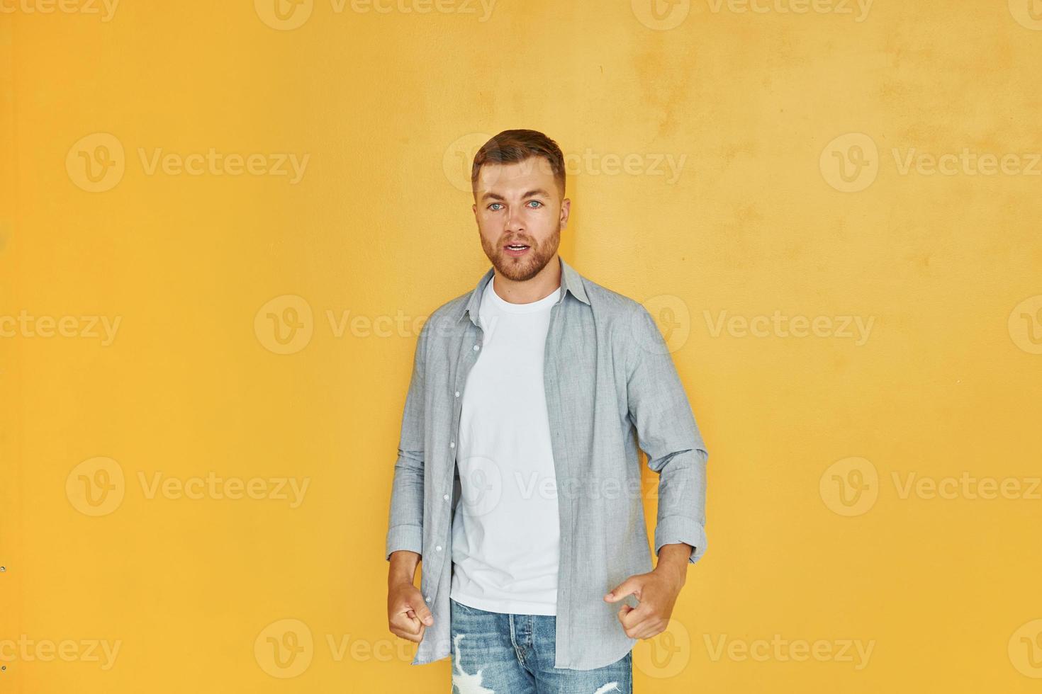 verspürt Wut. Junger Mann in Freizeitkleidung, der drinnen im Studio steht foto