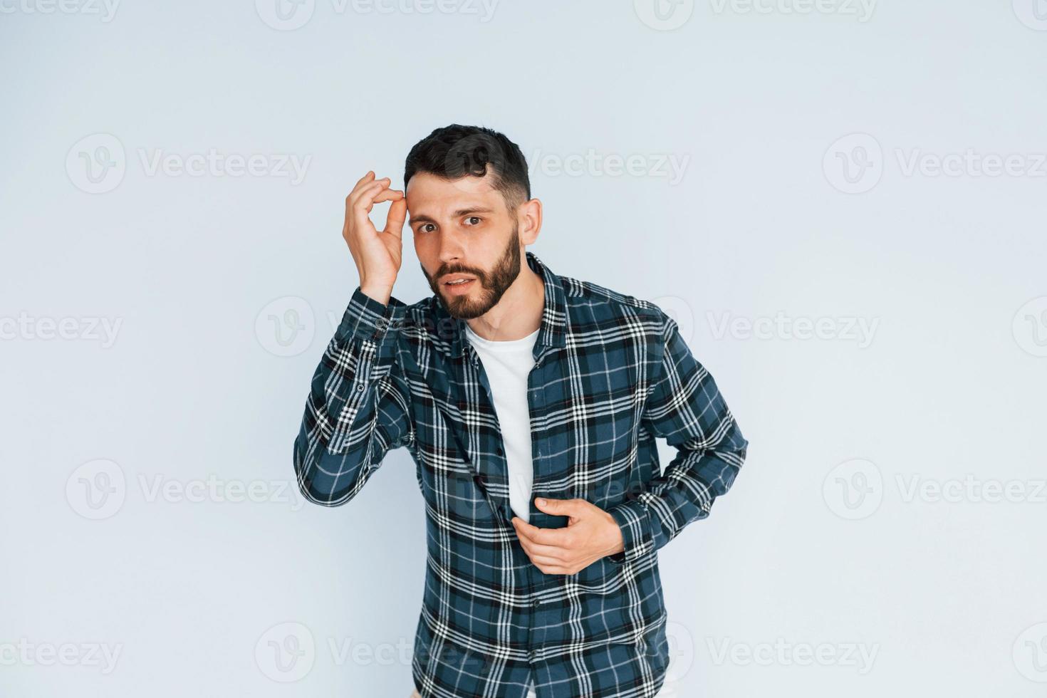 schaut in die Kamera. Junger Mann in Freizeitkleidung, der drinnen im Studio steht foto