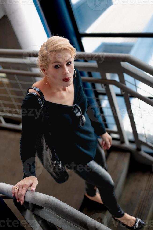 attraktive blonde Frau, die eine Treppe in einem Stadtgebäude hinuntergeht. foto