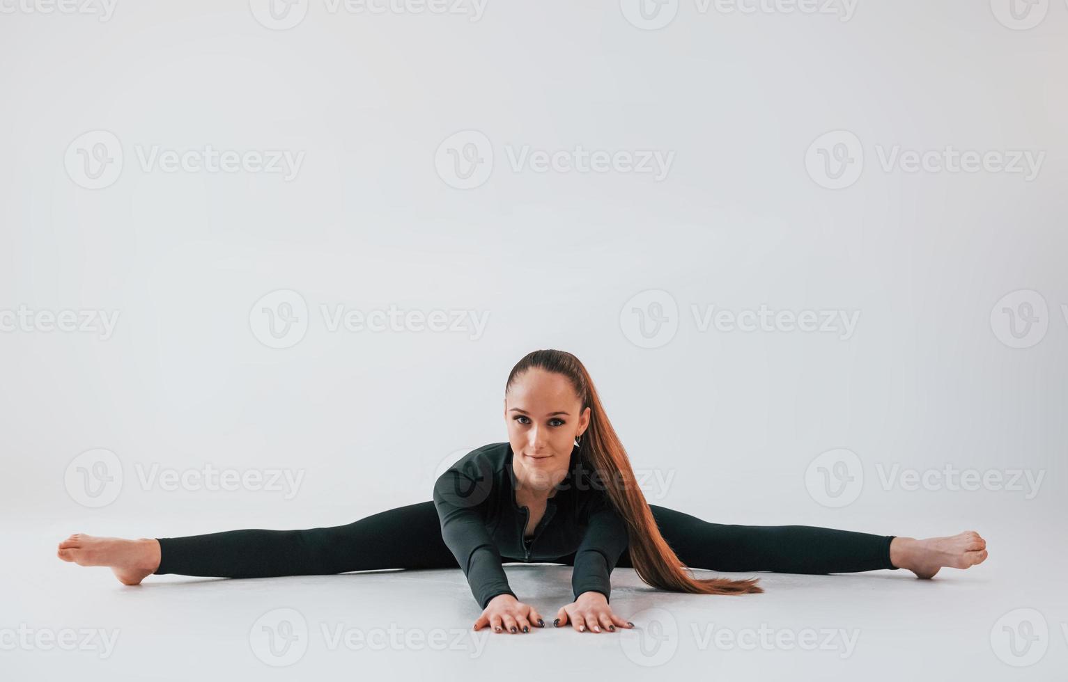 in schwarzer Kleidung. junge frau in sportlicher kleidung, die drinnen turnt foto