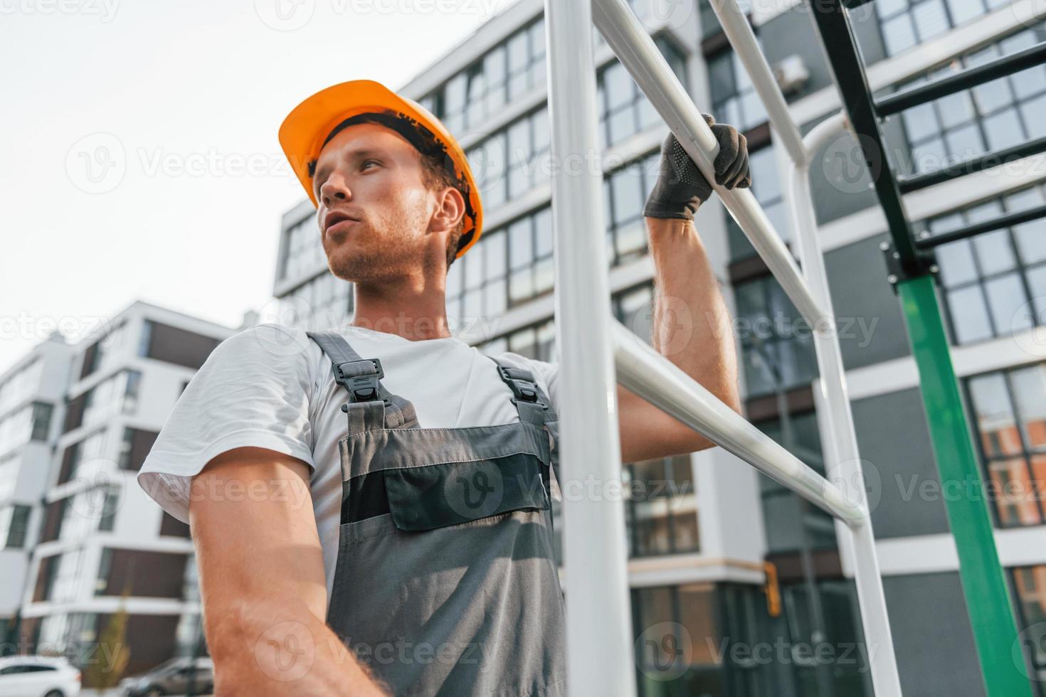 weit weg schauen. junger mann, der tagsüber in uniform auf dem bau arbeitet foto