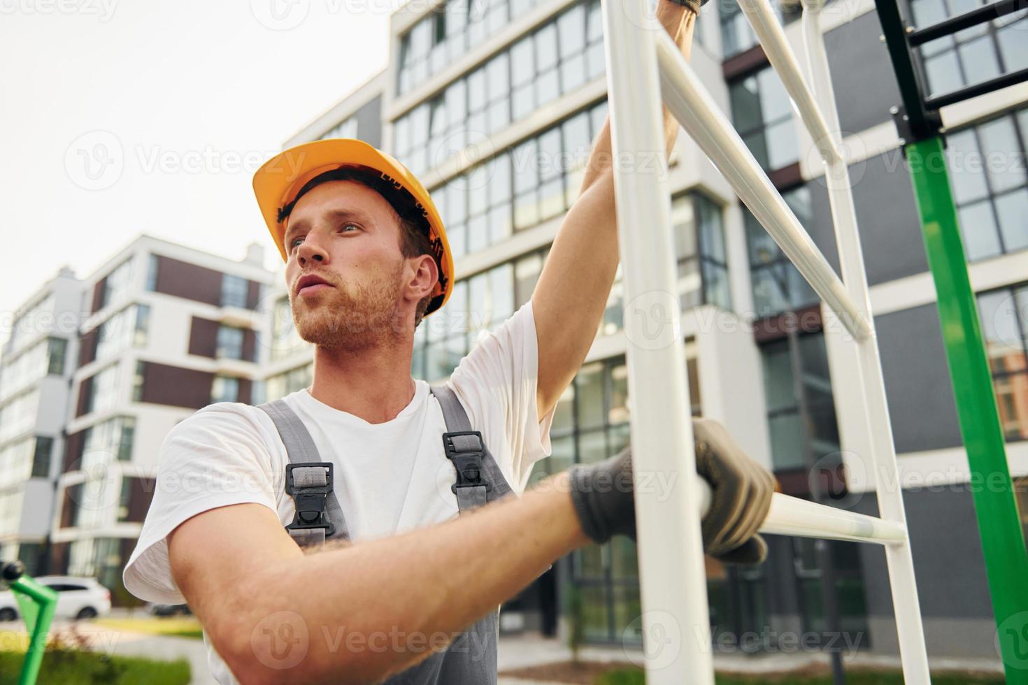 weit weg schauen. junger mann, der tagsüber in uniform auf dem bau arbeitet foto