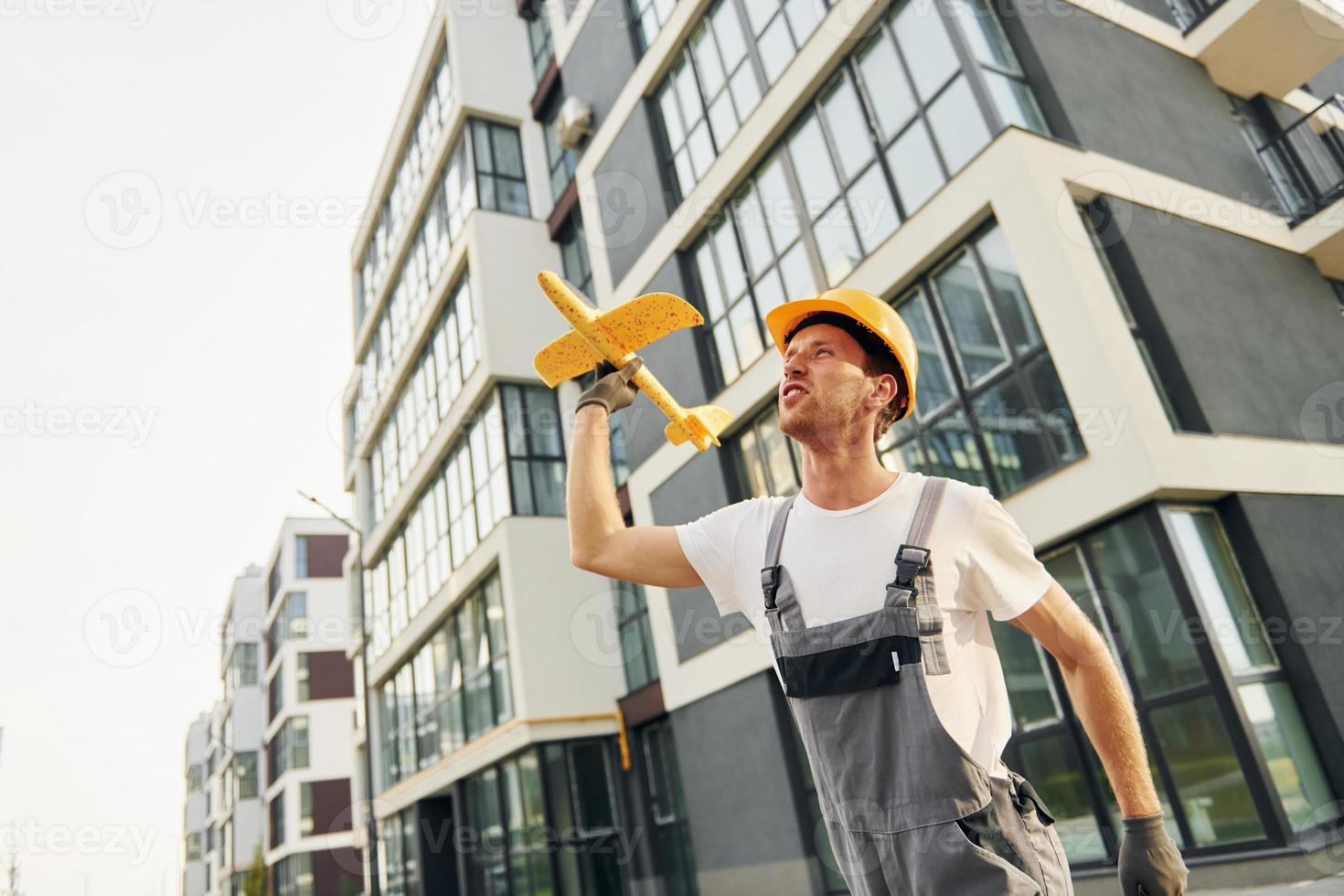 moderne Stadt. junger mann, der tagsüber in uniform auf dem bau arbeitet foto