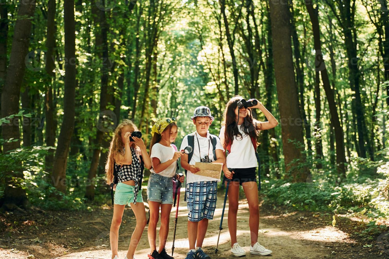 Suche nach dem Weg. kinder, die mit reiseausrüstung im wald spazieren gehen foto