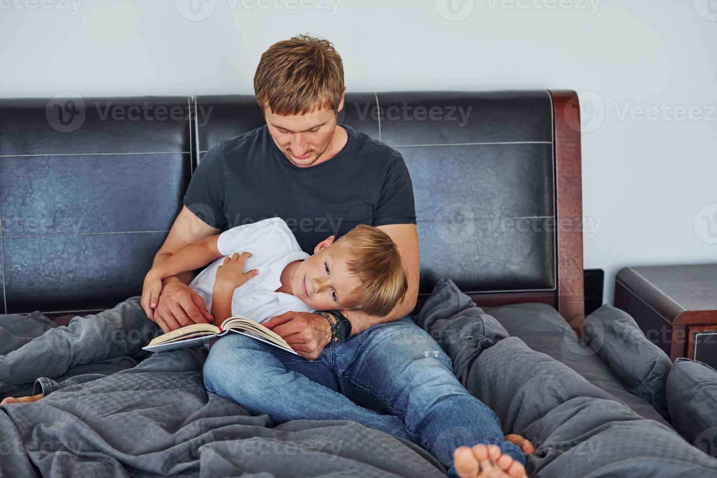 mit Buch in der Hand. Vater und Sohn sind zusammen zu Hause foto