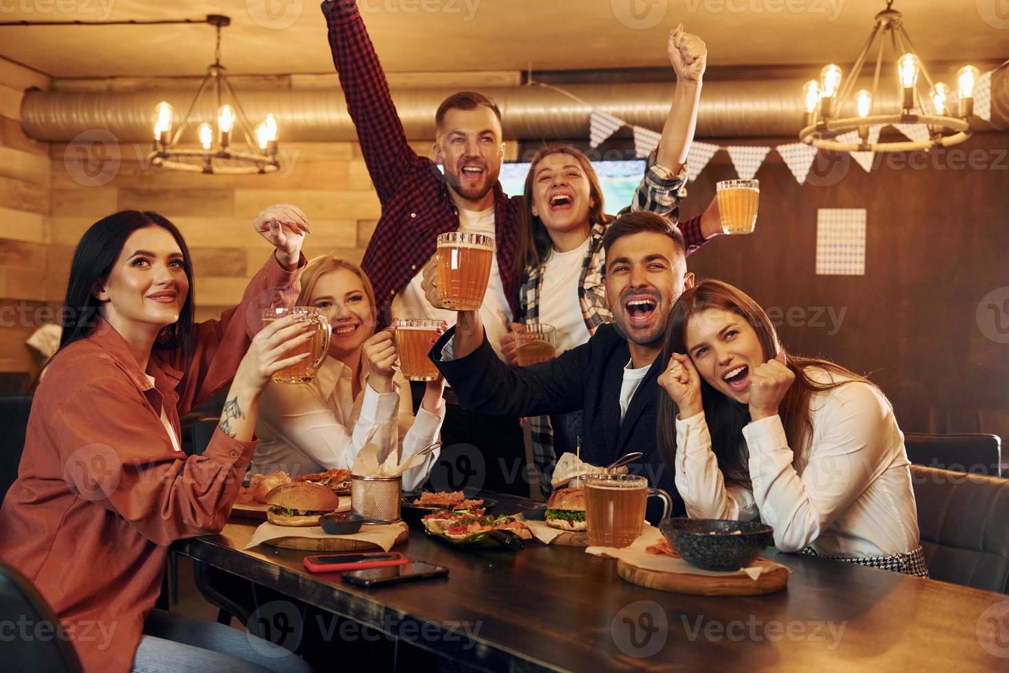 Fußballfans. gruppe junger freunde, die zusammen in der bar mit bier sitzen foto