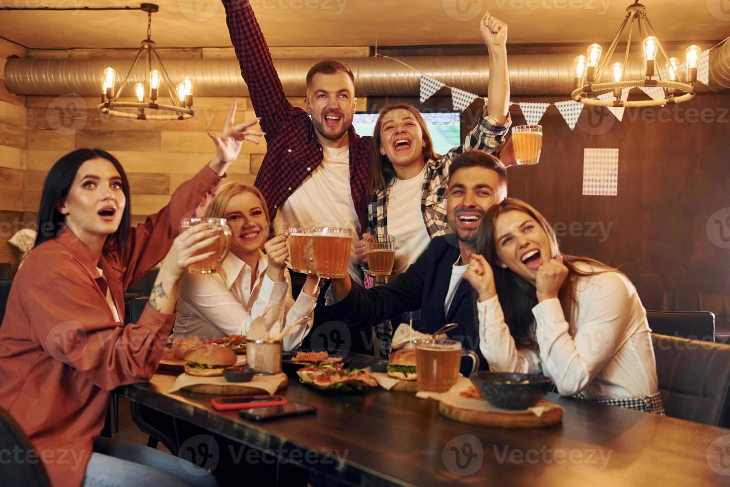 Fußballfans. gruppe junger freunde, die zusammen in der bar mit bier sitzen foto