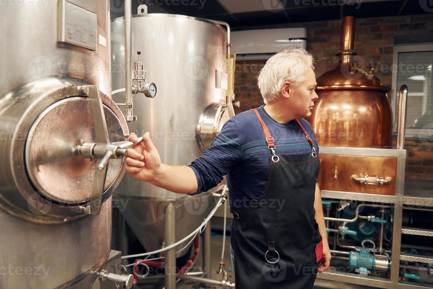 ein älterer mann steht mit ausrüstung für bier im lager foto