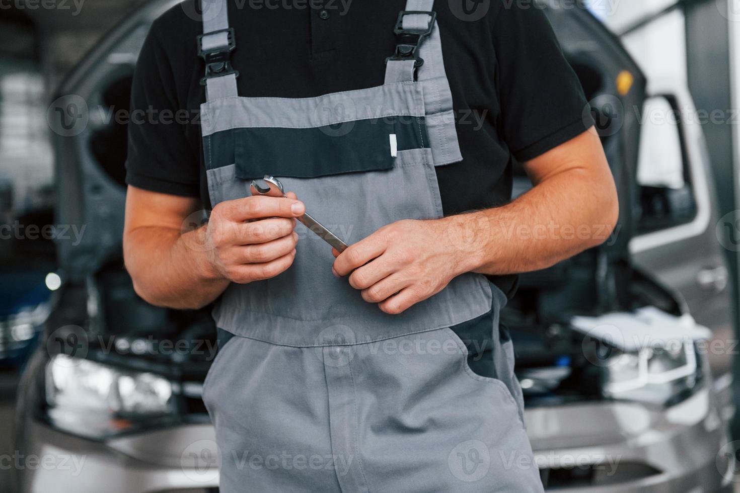 Nahaufnahme. Mann in Uniform arbeitet tagsüber im Autosalon foto