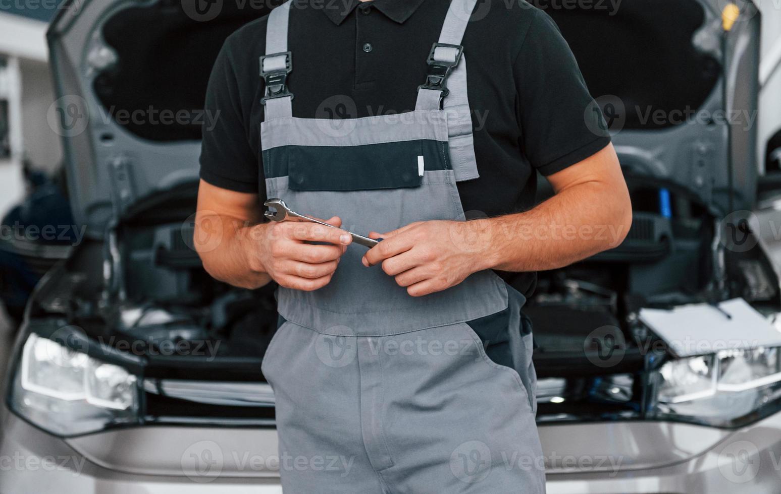 Nahaufnahme. Mann in Uniform arbeitet tagsüber im Autosalon foto