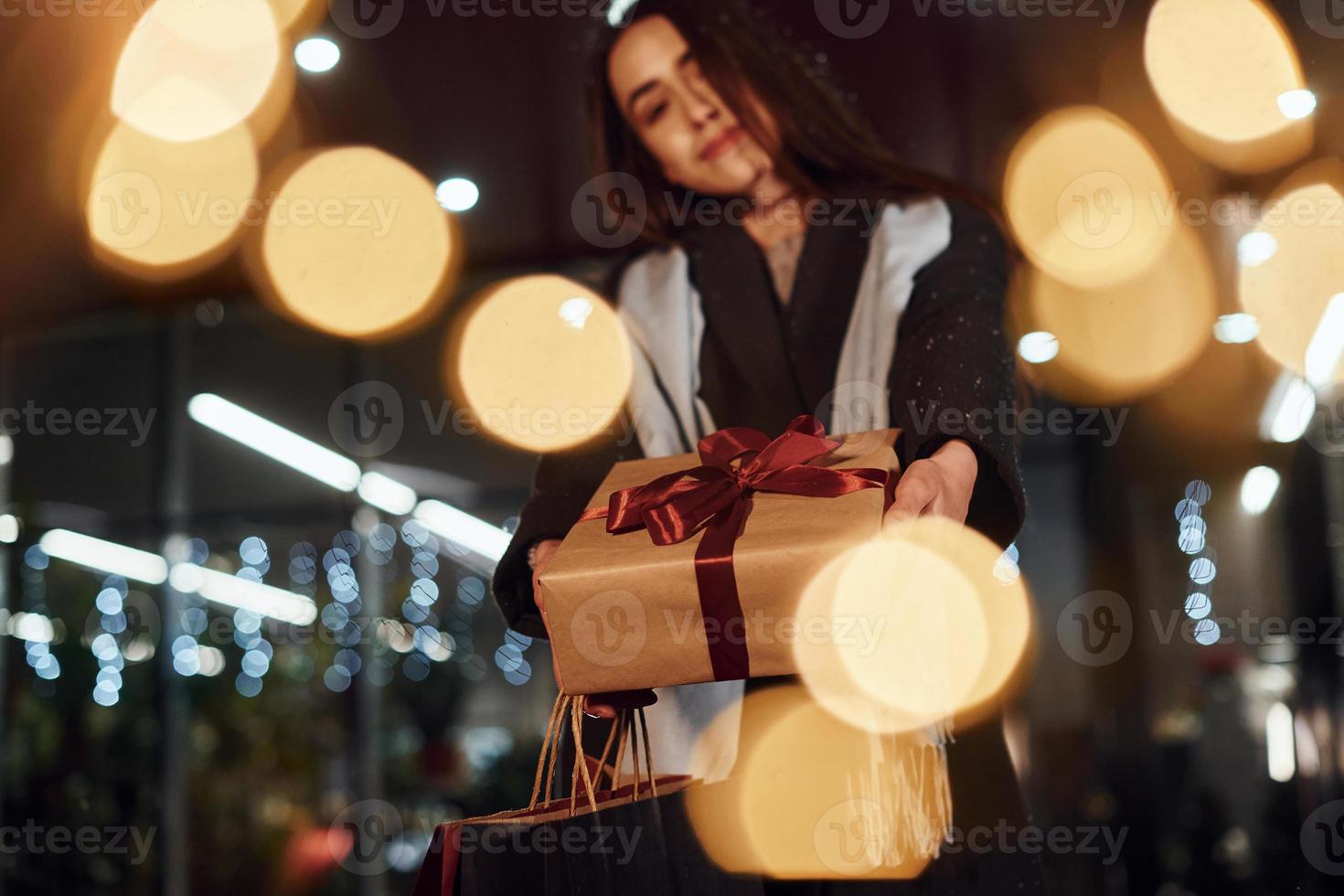 aus dem Shop mit Geschenkbox in den Händen. Fröhliche Frau ist in den Weihnachtsferien im Freien. Konzeption des neuen Jahres foto