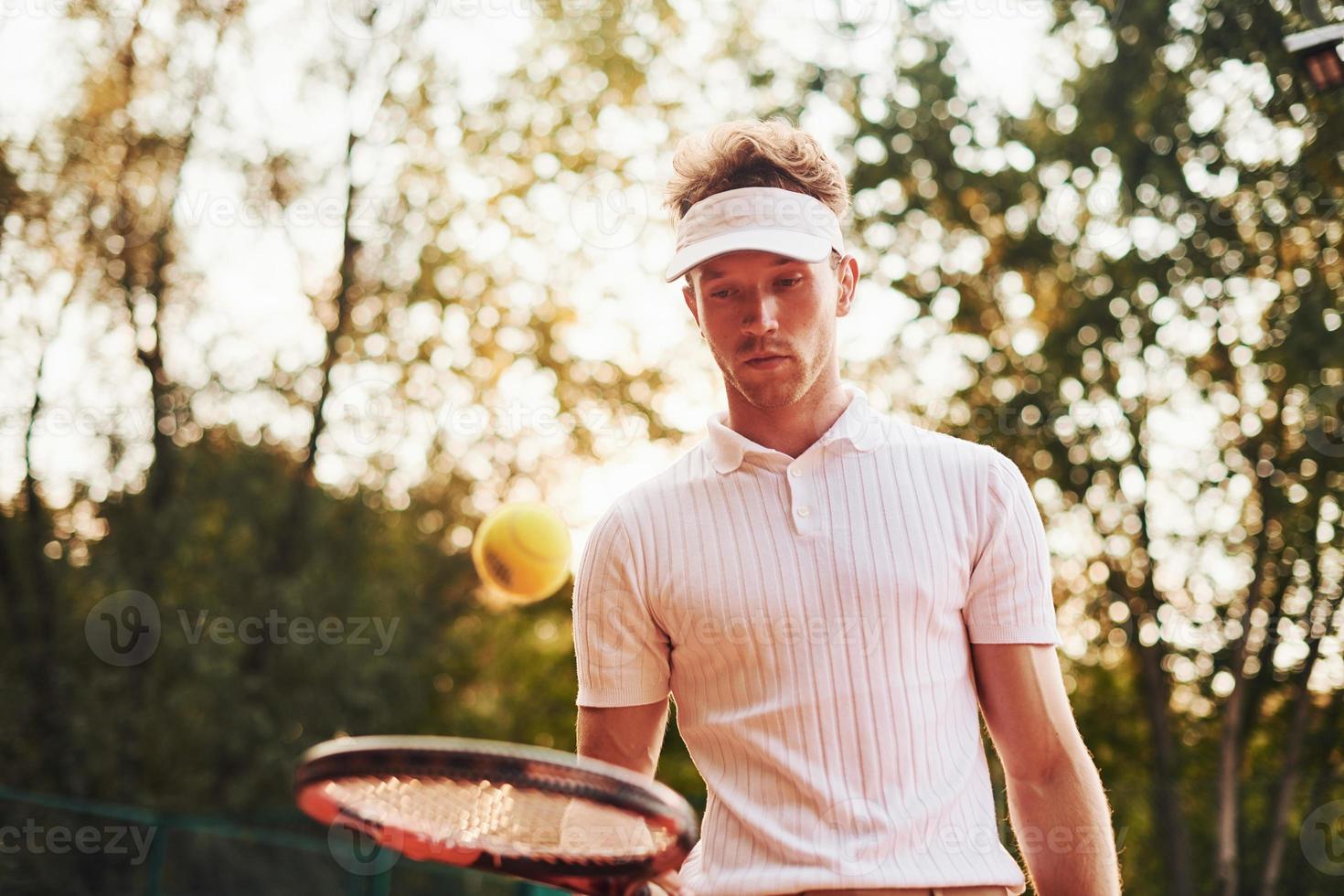 junger tennisspieler in sportlicher kleidung ist draußen auf dem platz foto