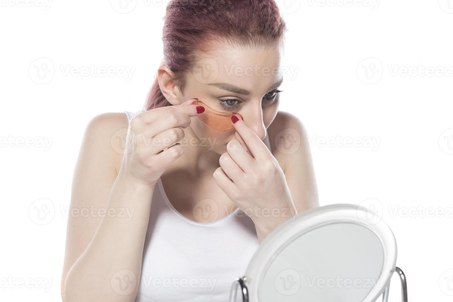 hübsche Frau mit kosmetischen Pflastern, die auf der Haut unter den Augen Feuchtigkeit spenden. isoliert auf weißem Hintergrund foto
