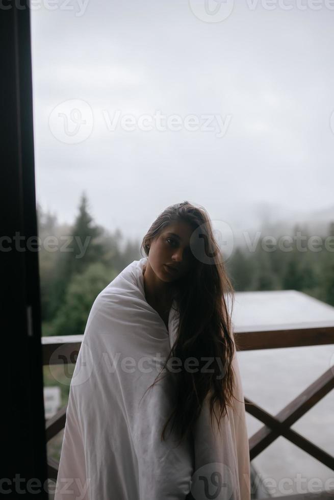 junge Frau in eine Decke gehüllt auf dem Balkon foto