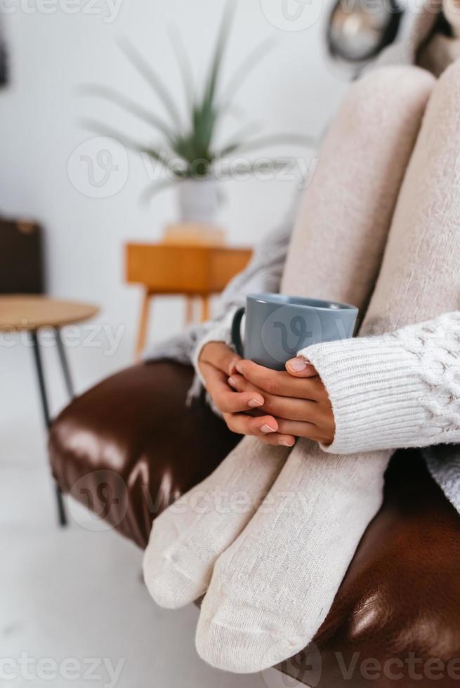 abgeschnittene Aufnahme einer sitzenden Frau, die einen Becher zu Füßen hält foto