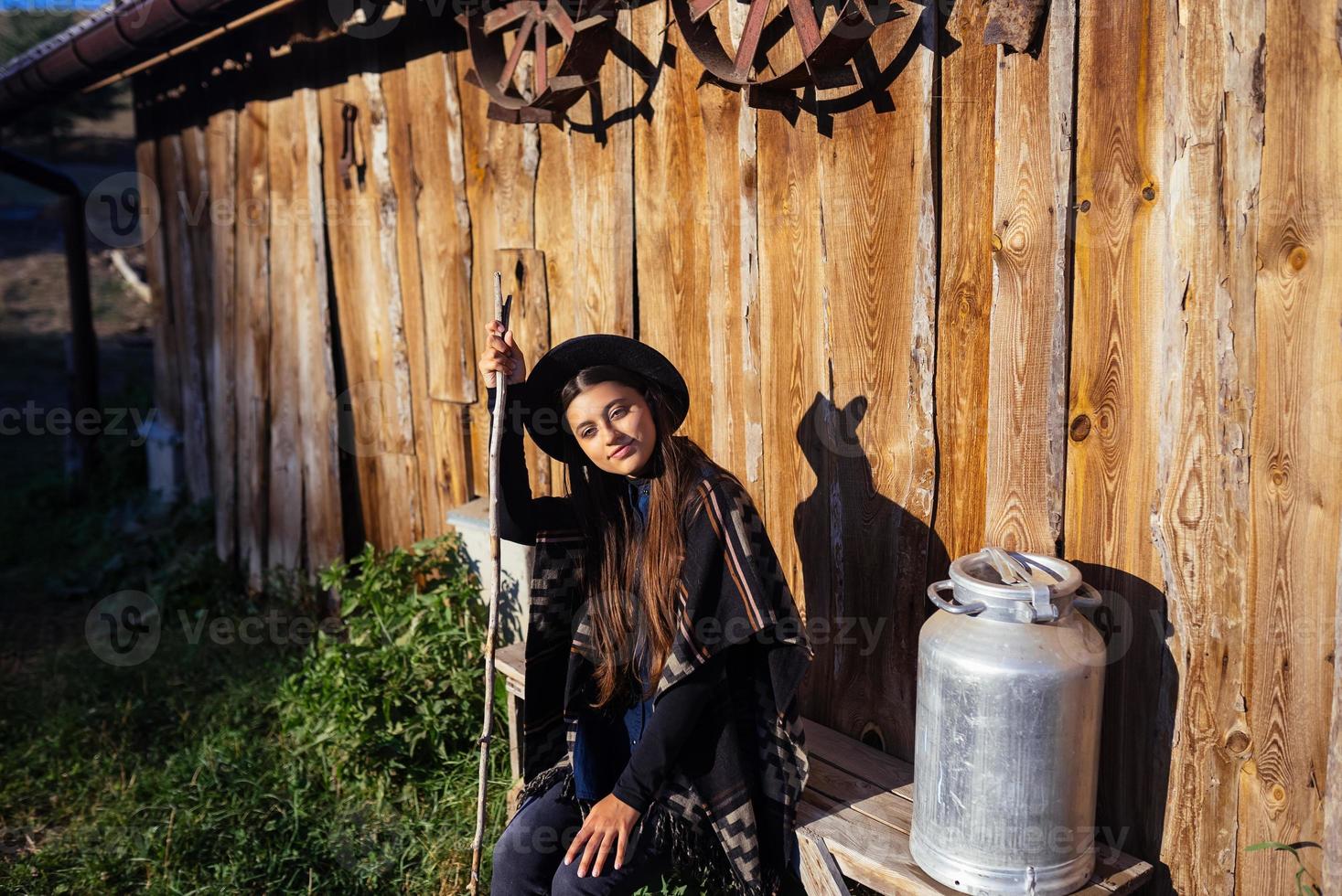 Frau sitzt auf einer Bank mit Milchkannen auf einem Bauernhof foto