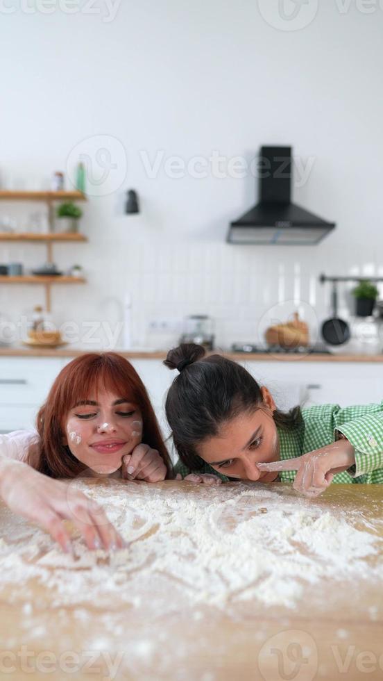 Zwei schöne Frauen spielen in der Küche mit Mehl foto