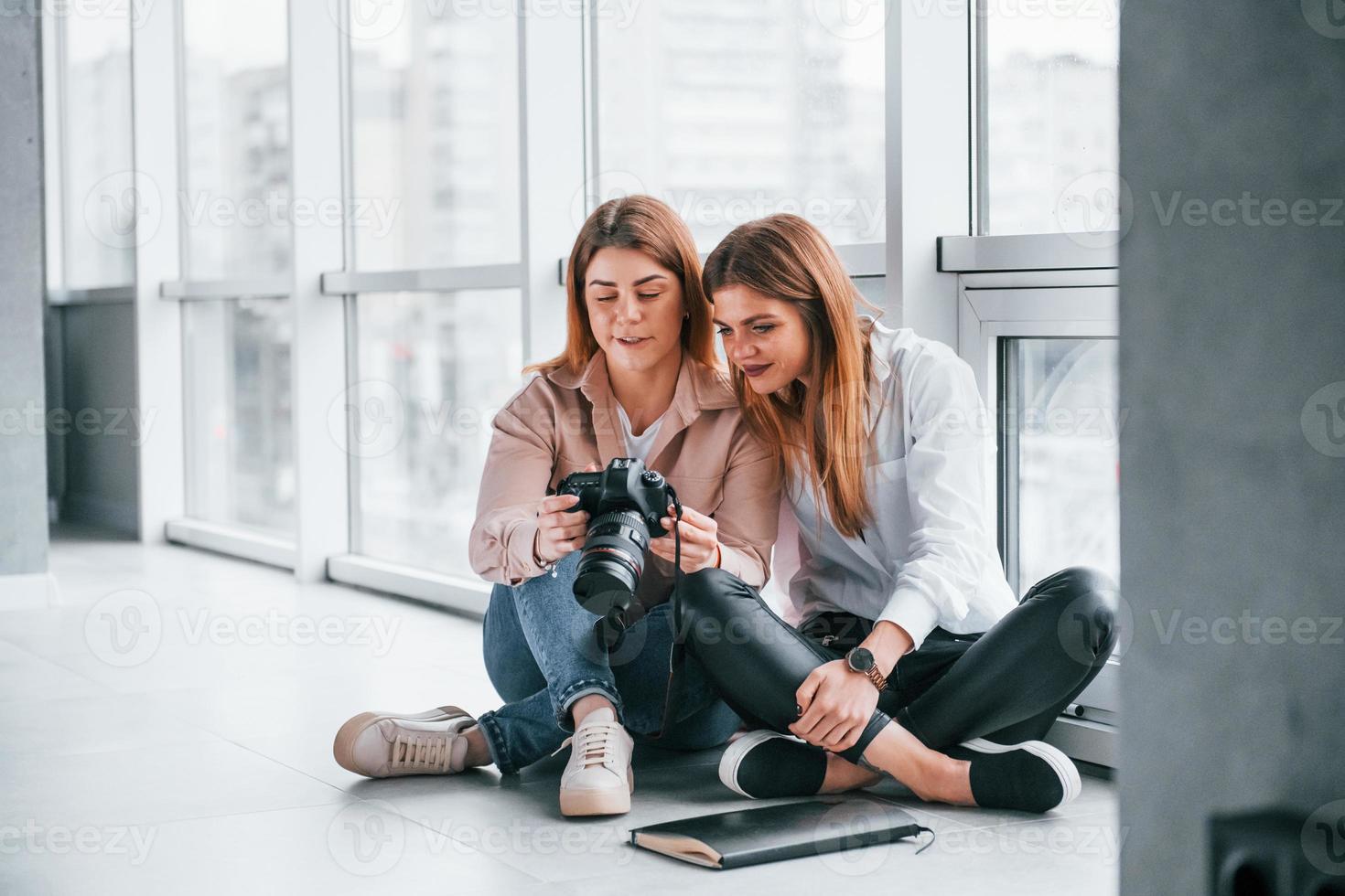 Zwei Frauen sitzen zusammen im Haus und sehen sich Fotos auf der Kamera an